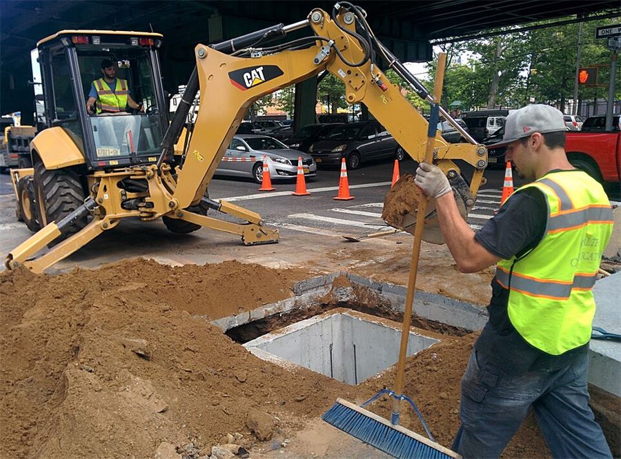 Fiber optic manhole installation in a road excavation