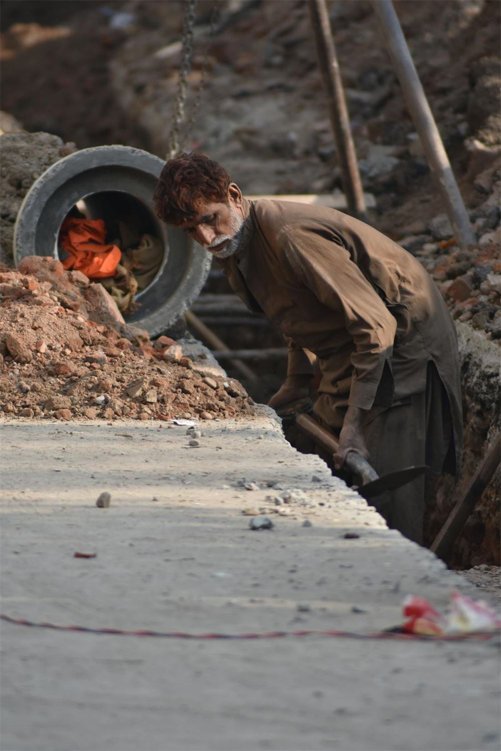 Worker inspecting pipe installation in an underground utility trench